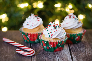 Christmas cupcakes with red and green sprinkles on rustic table. Shallow depth of field. Sparkling...