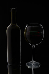 Glass of red wine with bottle