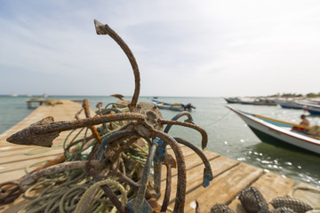 Details of a fishing boat anchor in the harbor of Boca de Pozo with the ocean and a clear blue sky in the background. Margarita Island. Venezuela 2015 (Selective focus)
