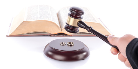 Hand holding a judge gavel above wedding rings