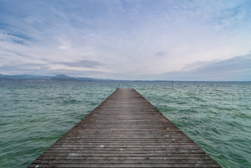 Obraz na płótnie Canvas wooden pier and cloudy sky over Garda lake - Italy