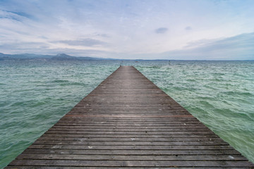 Fototapeta premium wooden pier and cloudy sky over Garda lake - Italy