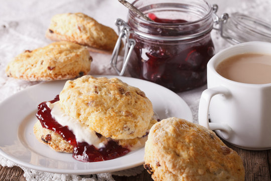Delicious English scones with jam and tea with milk close-up. Horizontal
