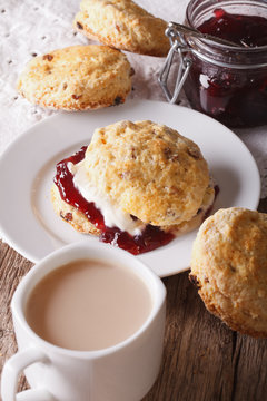 English pastries: scones with jam and tea with milk close-up. vertical
