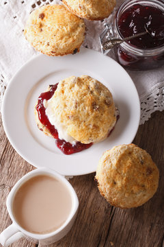 Delicious English scones with jam and tea with milk close-up. vertical
