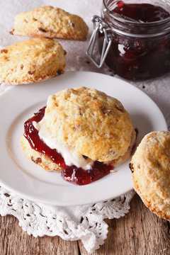 British scones with jam and whipped cream close-up. vertical
