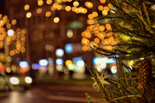 Branch of decorated Christmas tree in late evening on the street with night illumination