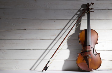 Vintage violin on the white wooden background.
