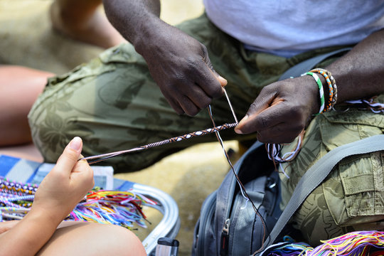 African Man Making String Bracelet On The Beach