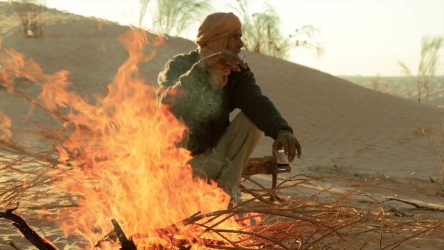 sahara man drinking coffee near a fire