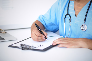 Portrait of unknown male surgeon doctor holding his stethoscope and filling up medical prescription