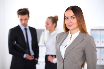 Pretty businesswoman in office with colleagues in the background