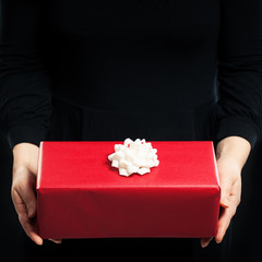 Red Gift Box and Female Hands on Black Background