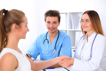 Male doctor and female patient shaking hands. Partnership, trust and medical ethics concept