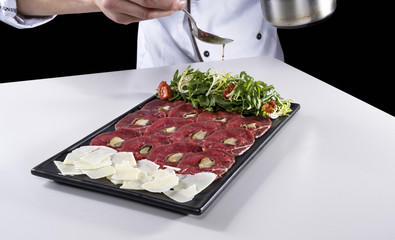 Meat carpaccio seasoned with olive oil by chief