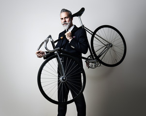 Portrait of a handsome middle aged man wearing suit and holding his classic bicycle on the shoulder