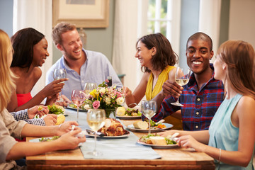 Friends At Home Sitting Around Table For Dinner Party