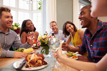Friends At Home Sitting Around Table For Dinner Party