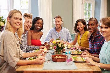 Friends At Home Sitting Around Table For Dinner Party