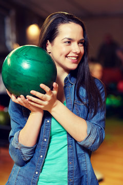 happy young woman holding ball in bowling club