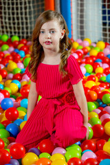 Fototapeta na wymiar A girl in the playing room with many little colored balls