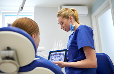 dentist showing x-ray on tablet pc to patient girl