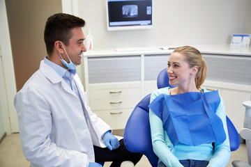 happy male dentist with woman patient at clinic