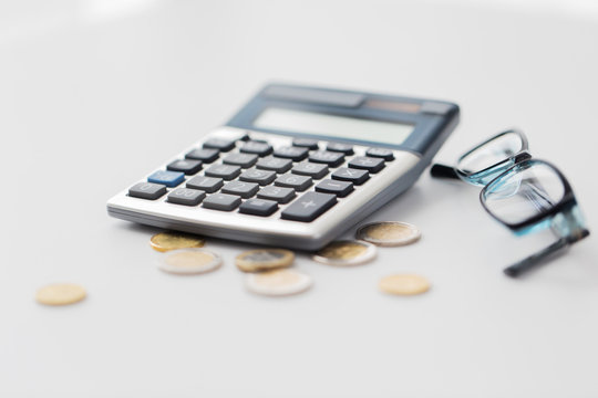 calculator, eyeglasses and coins on office table