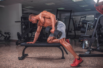 Muscular strong man exercise with weights in the gym.