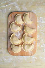 Sculpt pierogy and pelmeni concept. Include rustic cutting board, making pierogies on a rustic wooden table. Dumpling recipe.