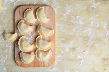 Sculpt pierogy and pelmeni concept. Include rustic cutting board, making pierogies on a rustic wooden table. Dumpling recipe.