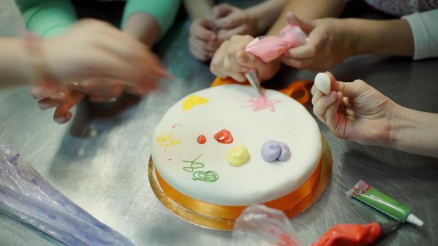 The children hands are painting on the cake