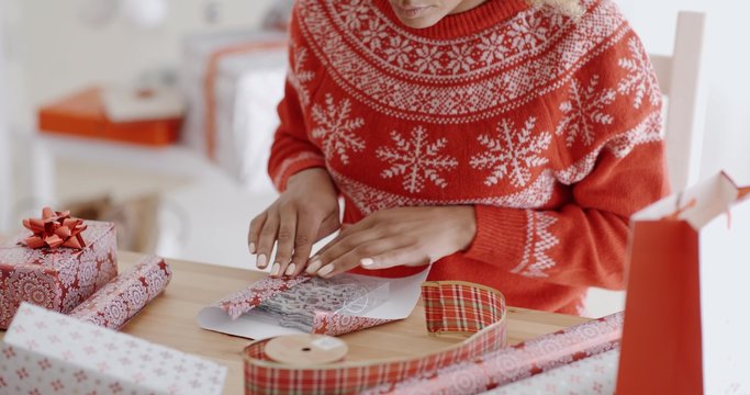Young woman carefully wrapping a Christmas gift