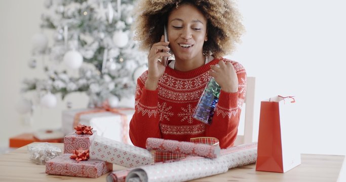 Woman chatting on a mobile as she wraps gifts