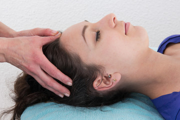 Fototapeta na wymiar Young bright woman receiving a head massage in a spa center