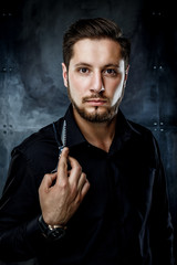 Elegant young handsome man. Studio fashion portrait.Man holding scissors and provocatively looking at camera