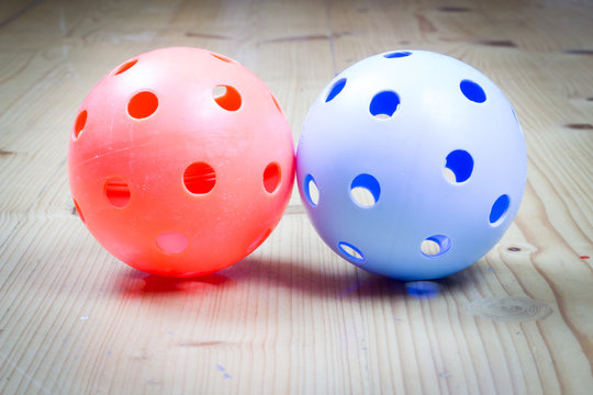 Two types of florbal balls on the wooden floor, sport