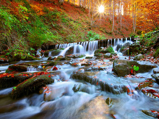Fototapeta na wymiar Beautiful waterfall in forest at sunset