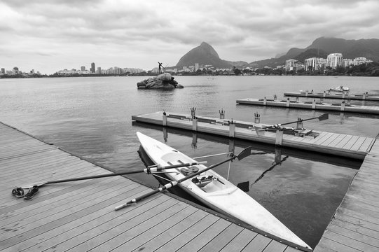 Rowing boat with oars docked at a wood pier on the Lagoa Rodrigo de Freitas lagoon with a view of of the Rio de Janeiro Brazil skyline