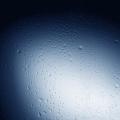 Water drops on glass against blue background