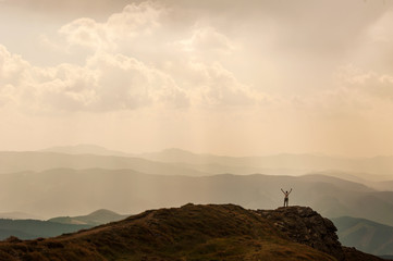 Man stands near the cross on top of mountain