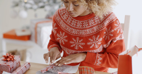 Young woman carefully wrapping a Christmas gift
