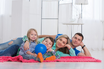 Happy family having fun on the floor in white interior