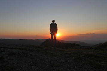 A man stands on the mountain and greets the rising sun