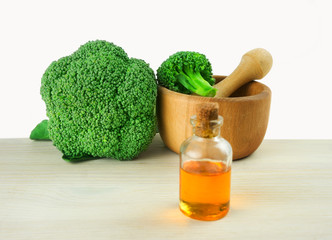 Fresh Broccoli in wooden mortar and seed oil in vintage bottle