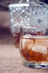 Carafe and glass of whisky, whiskey bourbon on a burlap, sacks background