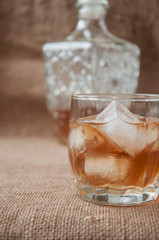 Carafe and glass of whisky, whiskey bourbon on a burlap, sacks background