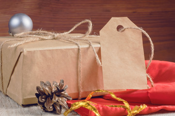 Gift box packed brown paper and twine with blank tag decorated holiday accessories on wooden table