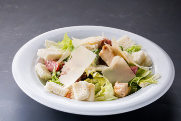 Caesar salad with chicken and greens on wooden table