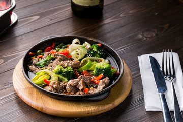 beef stew with vegetables in a frying pan over dark background